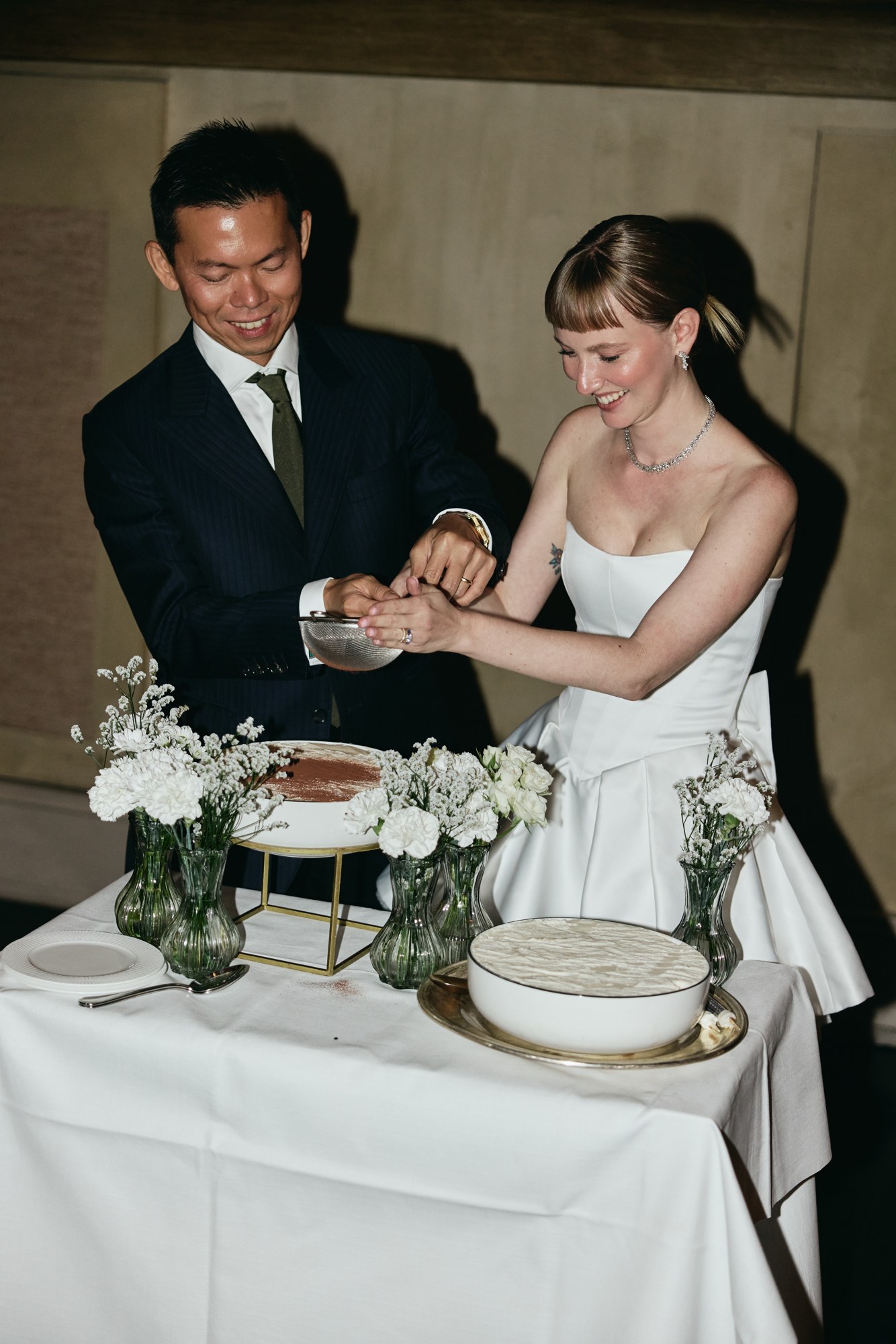 Lina and Jin smiling as they cut their wedding cake